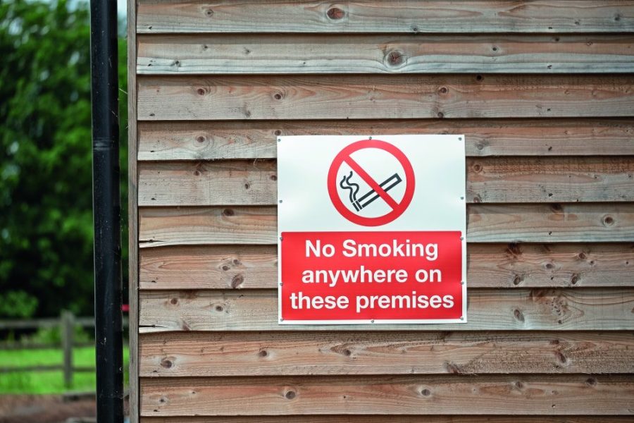London, UK - Circa June 2019: Newly attached No Smoking Sign seen nailed to a wooden building at a livery and horse yard. The sign warns visitors that No Smoking is forbidden within the stable block.