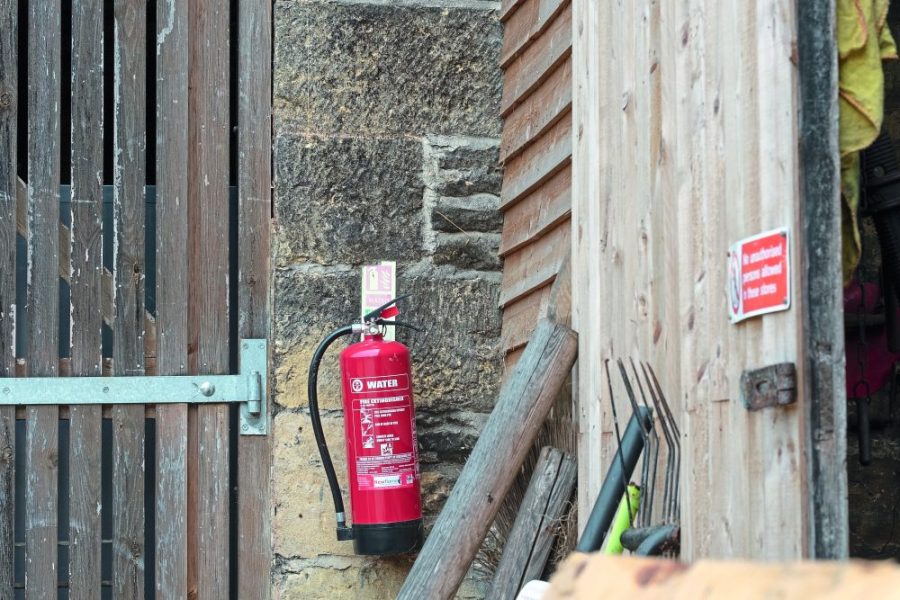 Newmarket, Cambridgeshire, UK - Circa June 2019: Shallow focus of a water type fire extinguisher seen attached to the outside of a barn door, the barn used to store straw for horses at a livery yard.