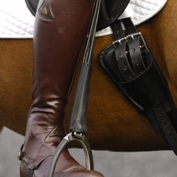 Pictured is a rider's foot in the stirrup, which attaches to the saddle with a stirrup leather. All are essential items of horse tack