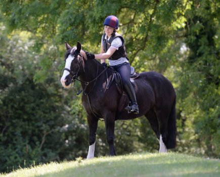 Pictured is a rider patting her cob while out hacking; it is important to address any fear you feel while riding a horse