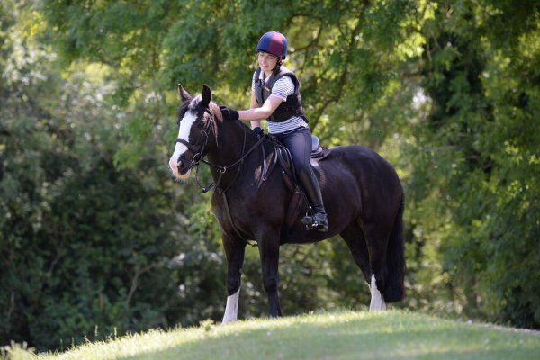 Pictured is a rider patting her cob while out hacking; it is important to address any fear you feel while riding a horse